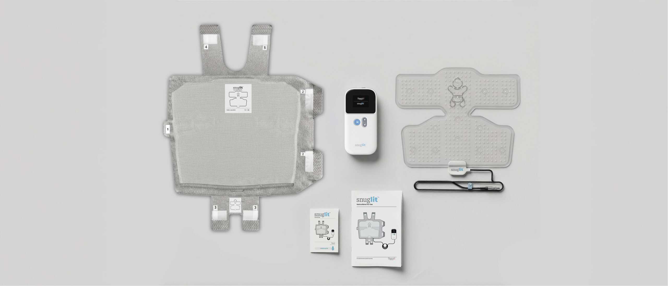 A display of Snuglit phototherapy items including the wearable phototherapy device, the fabric wrap, the controller, the instruction pamphlet