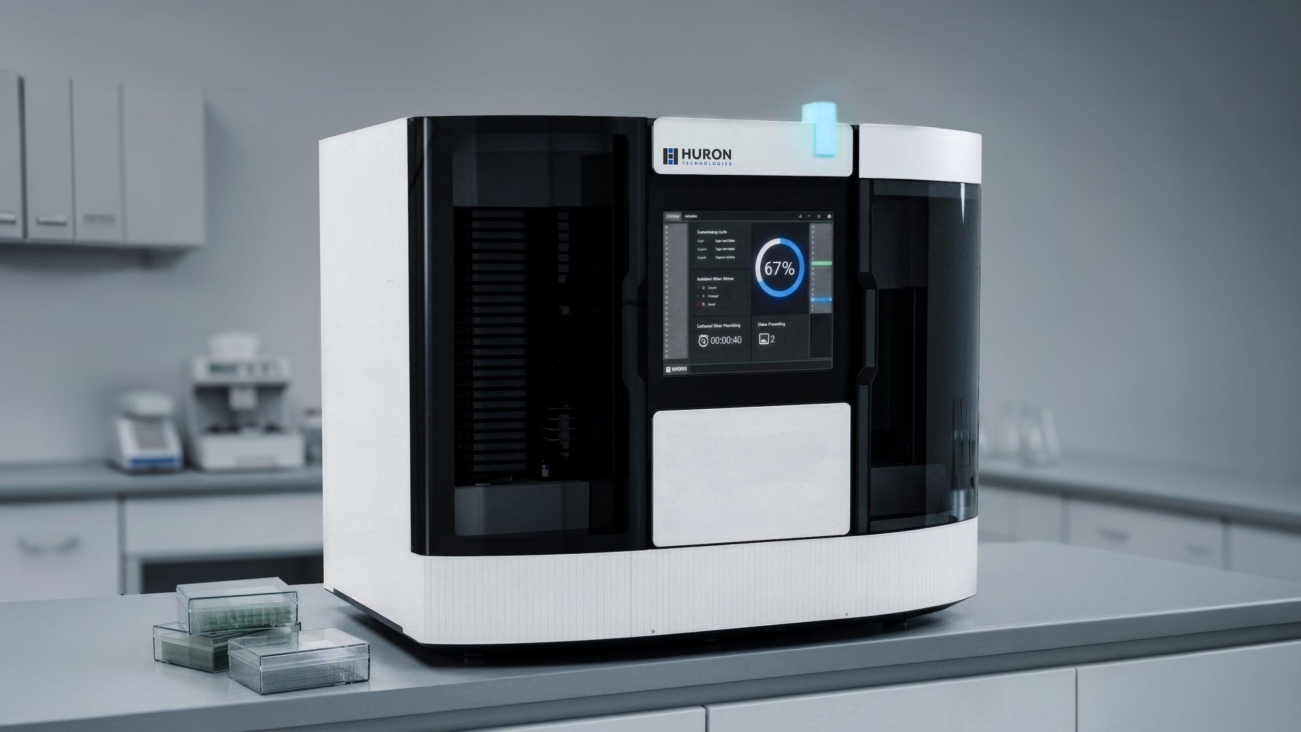 Huron Technologies medical device with touchscreen interface on a lab bench, with trays and accessories placed nearby.