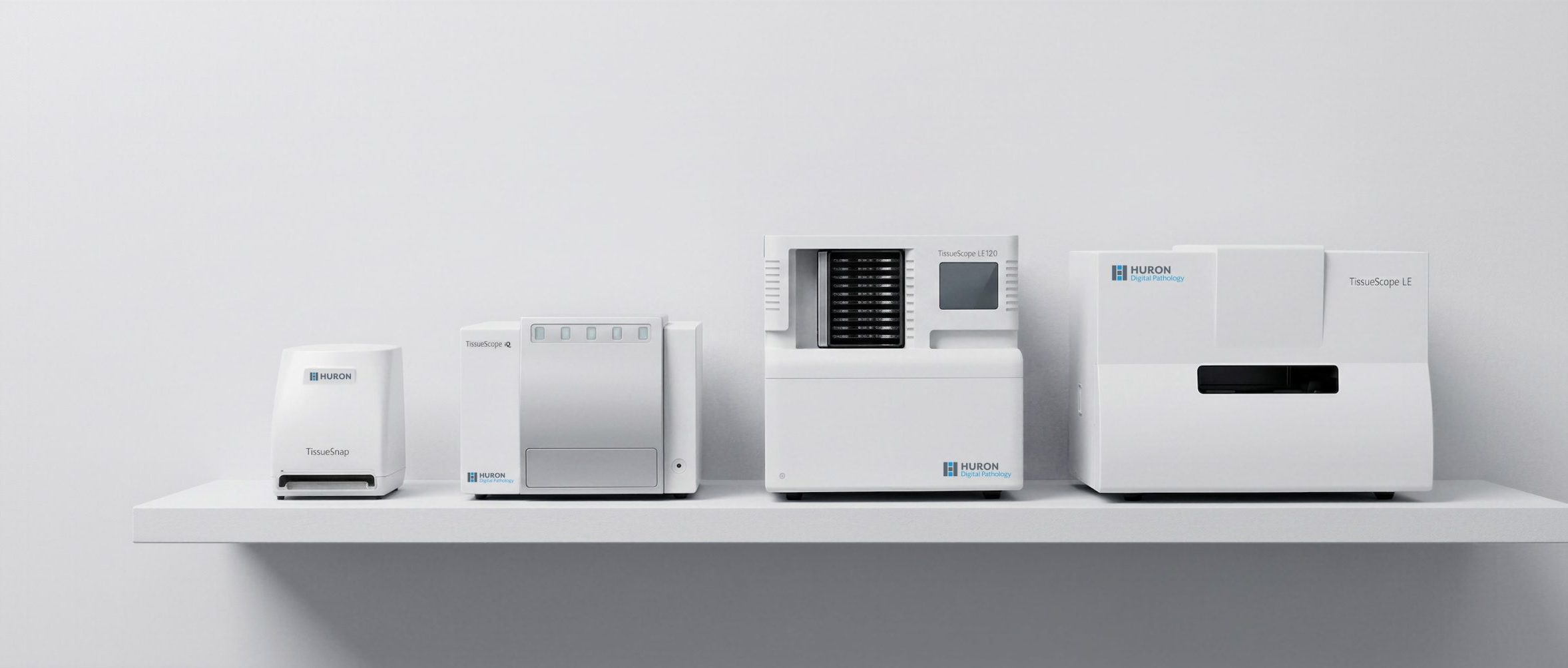 Huron Technologies digital pathology slide scanning devices arranged side by side, showing multiple medical imaging systems in a clean, white laboratory-style setting.