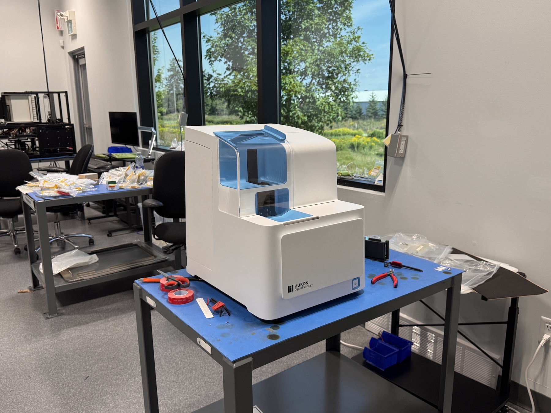 Huron Digital Pathology medical device prototype placed on a workbench with tools and components in a workshop environment.